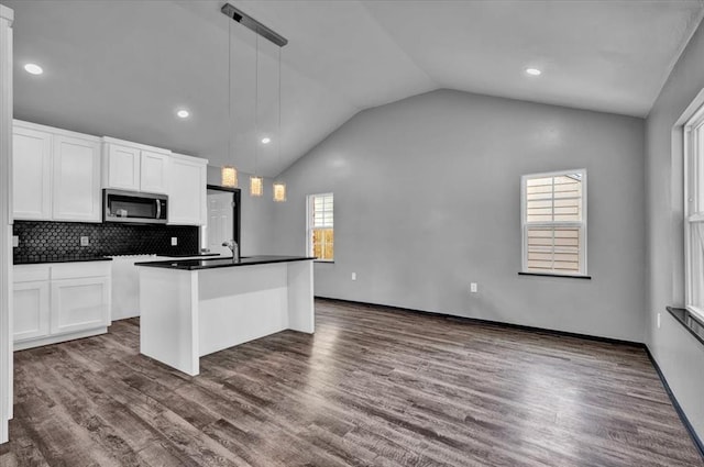 kitchen featuring a wealth of natural light, dark wood-type flooring, an island with sink, and pendant lighting