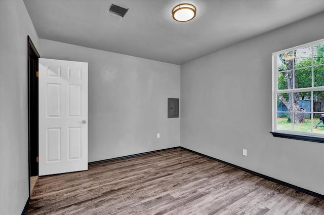 empty room featuring light wood-type flooring and electric panel