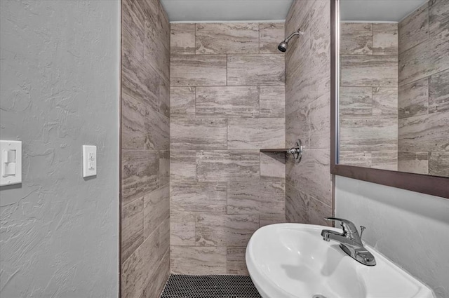 bathroom featuring a tile shower and sink