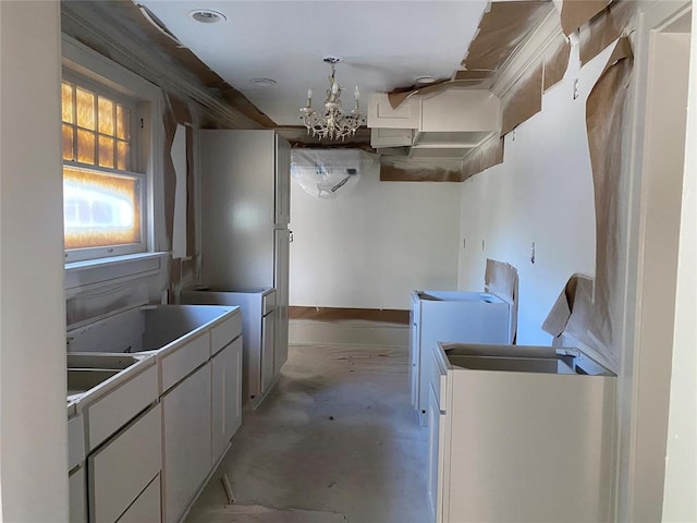 kitchen with white cabinets, washer / dryer, and a chandelier