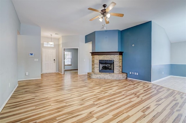 unfurnished living room with a brick fireplace, ceiling fan, and light hardwood / wood-style flooring