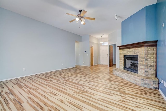 unfurnished living room featuring a brick fireplace, ceiling fan, and light hardwood / wood-style flooring