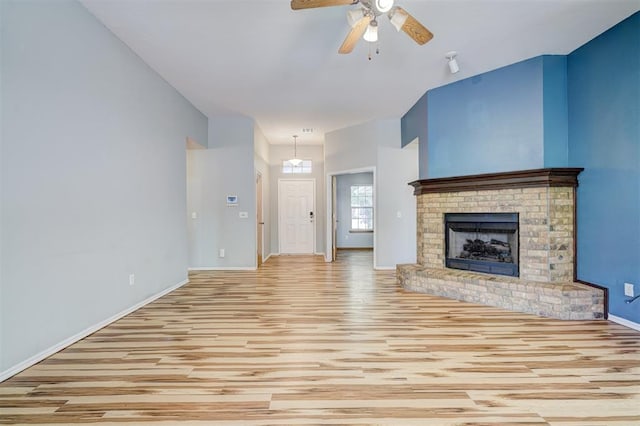 unfurnished living room featuring light hardwood / wood-style floors, a brick fireplace, and ceiling fan