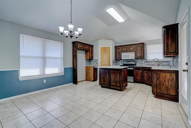 kitchen featuring lofted ceiling, hanging light fixtures, stainless steel range, a notable chandelier, and a kitchen island