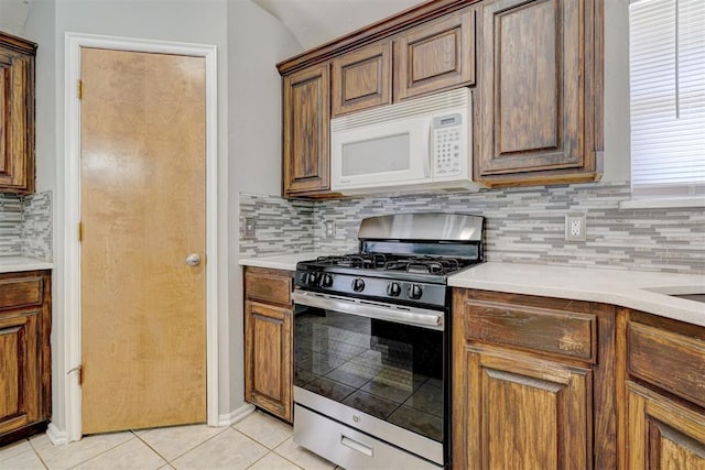 kitchen featuring light tile patterned floors, gas stove, and tasteful backsplash