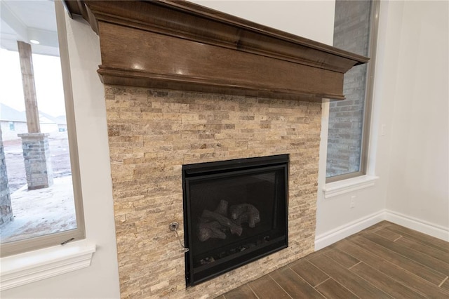 interior details with a glass covered fireplace, baseboards, and wood tiled floor