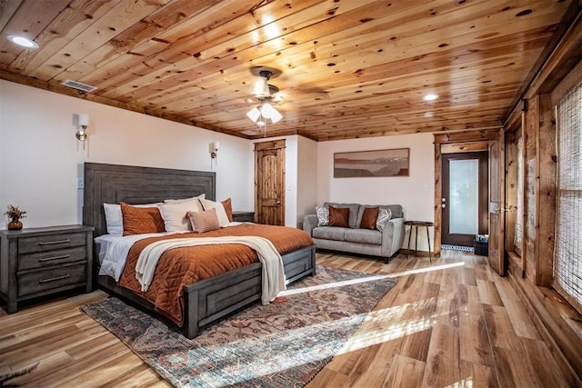 bedroom with ceiling fan, light hardwood / wood-style floors, wooden ceiling, and wooden walls