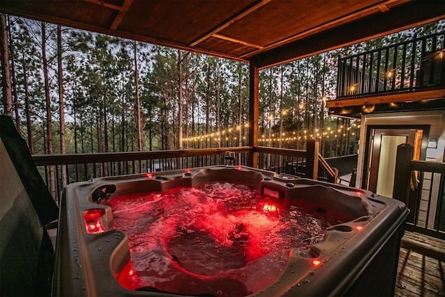 deck at dusk featuring a hot tub