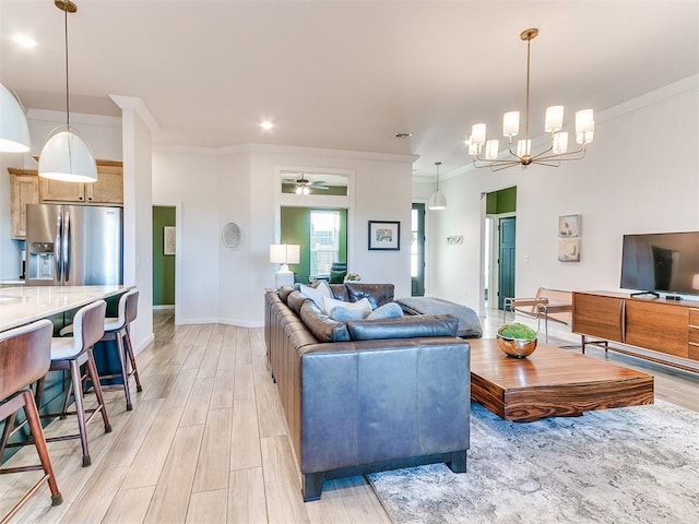 living room with crown molding, ceiling fan with notable chandelier, and light wood-type flooring