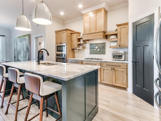 kitchen featuring pendant lighting, stainless steel appliances, light brown cabinetry, and a kitchen island with sink