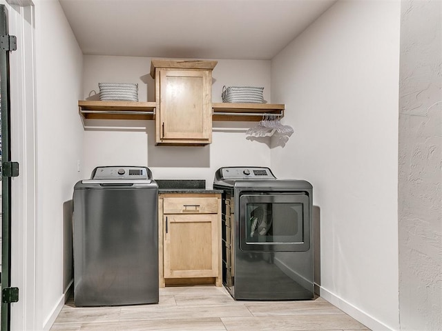 laundry area featuring cabinets, washer and dryer, and light hardwood / wood-style flooring