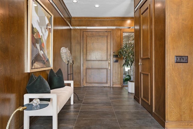 hallway featuring dark tile patterned flooring and wooden walls