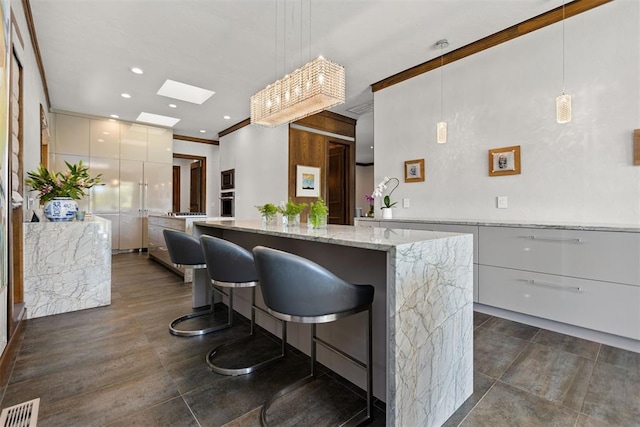 kitchen with appliances with stainless steel finishes, white cabinetry, hanging light fixtures, and a kitchen island