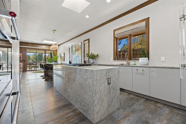 kitchen featuring a kitchen island, a skylight, white cabinetry, and a healthy amount of sunlight