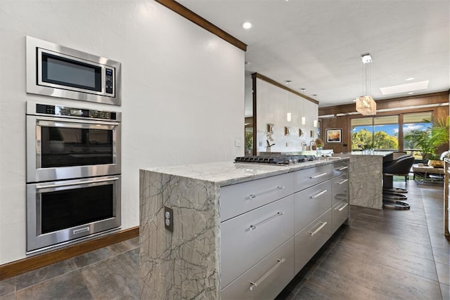 kitchen with gray cabinets, decorative light fixtures, a kitchen island, and appliances with stainless steel finishes