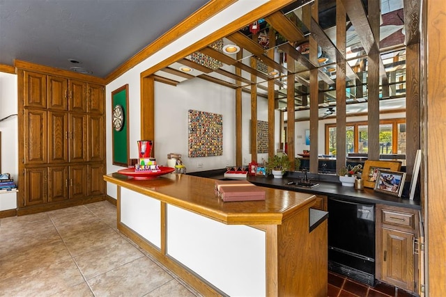 kitchen featuring dishwasher, light tile patterned flooring, kitchen peninsula, and sink