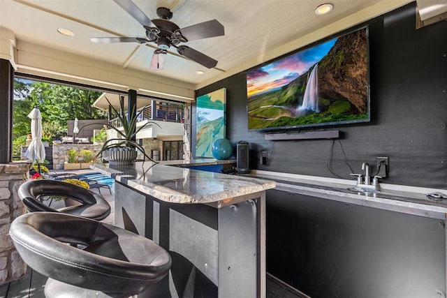 view of patio featuring ceiling fan and a bar