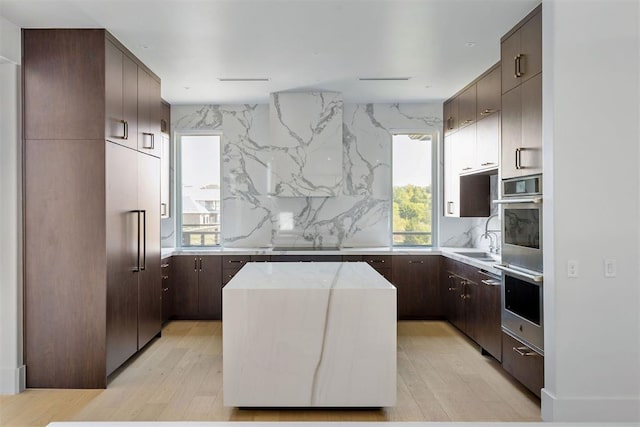 kitchen with decorative backsplash, appliances with stainless steel finishes, sink, a center island, and light hardwood / wood-style floors