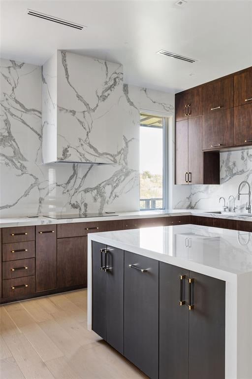 kitchen featuring dark brown cabinets, light hardwood / wood-style flooring, sink, and tasteful backsplash