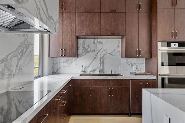 kitchen featuring light hardwood / wood-style flooring, decorative backsplash, black electric cooktop, range hood, and double oven