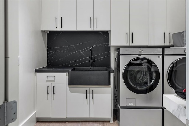 washroom with cabinets, independent washer and dryer, and sink