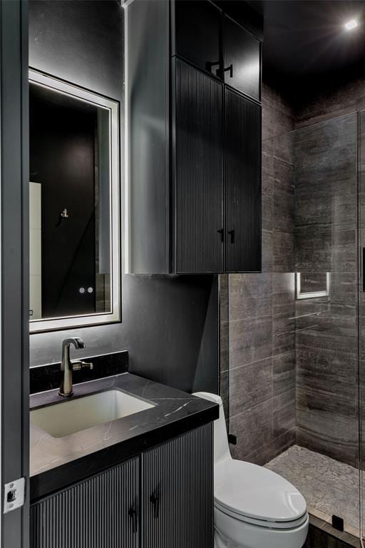 bathroom with a tile shower, vanity, and toilet