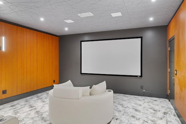 carpeted home theater featuring wood walls