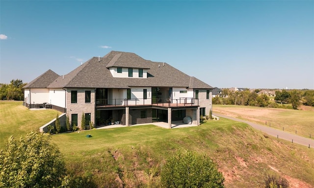 rear view of house with a lawn, a wooden deck, and a patio