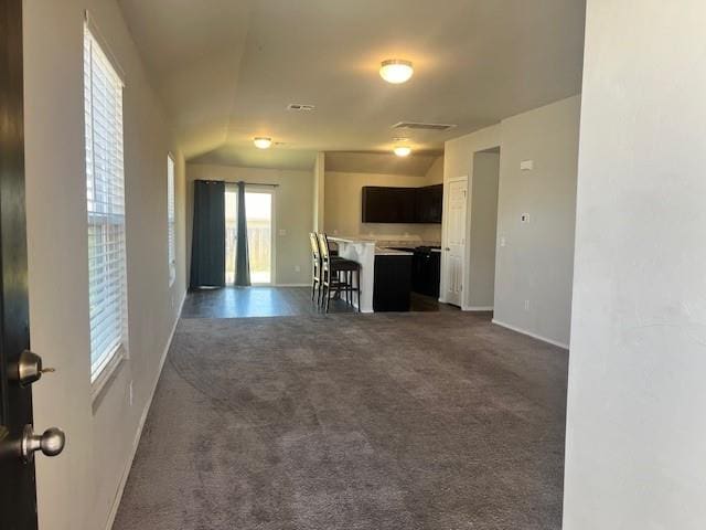 interior space with a kitchen bar, a center island, and dark carpet