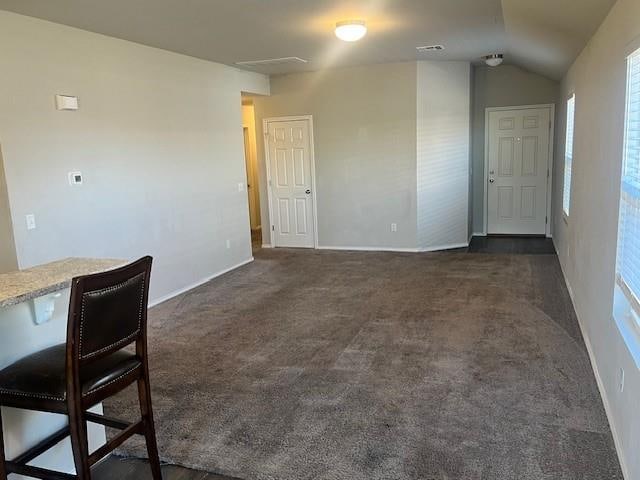 interior space featuring dark carpet and vaulted ceiling