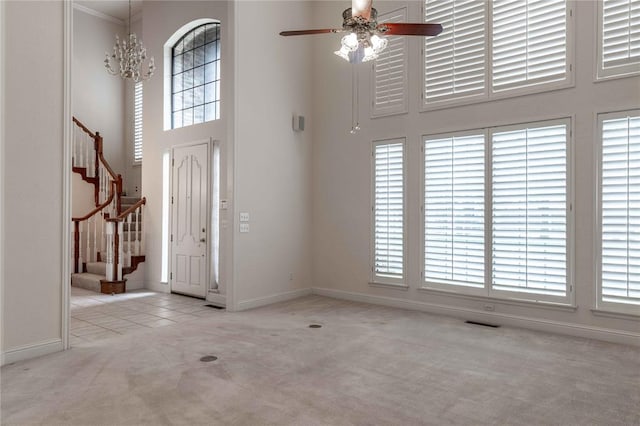 foyer entrance featuring light carpet, a healthy amount of sunlight, stairs, and a high ceiling