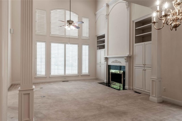 unfurnished living room with light carpet, a premium fireplace, ceiling fan with notable chandelier, and a towering ceiling