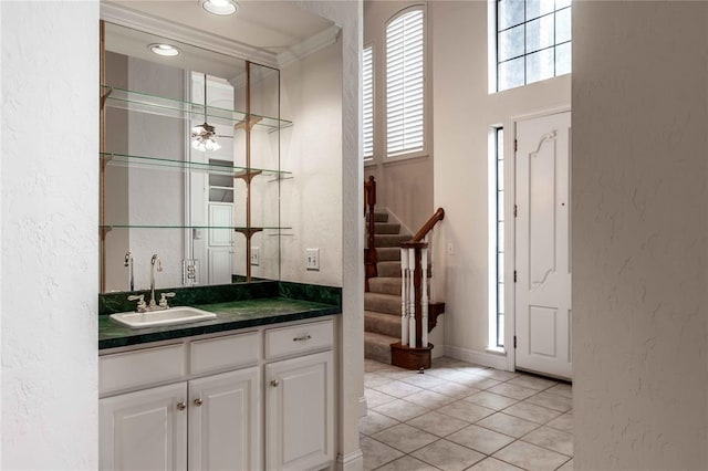 bar featuring a textured wall, pendant lighting, a sink, and stairway