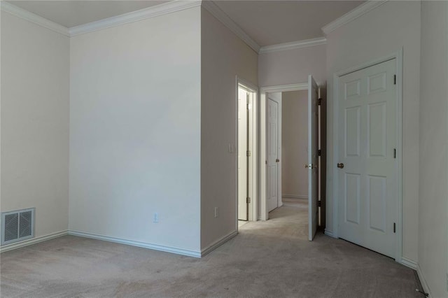 empty room featuring baseboards, ornamental molding, visible vents, and light colored carpet