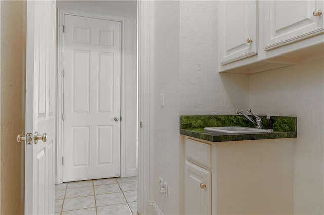 interior space featuring a textured wall, light tile patterned flooring, and a sink