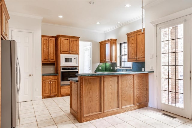 kitchen with stainless steel appliances, a peninsula, visible vents, brown cabinets, and dark countertops