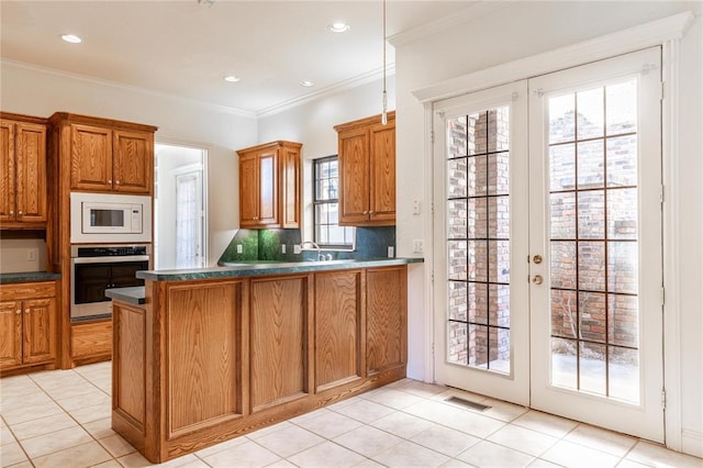 kitchen with dark countertops, visible vents, white microwave, brown cabinetry, and stainless steel oven