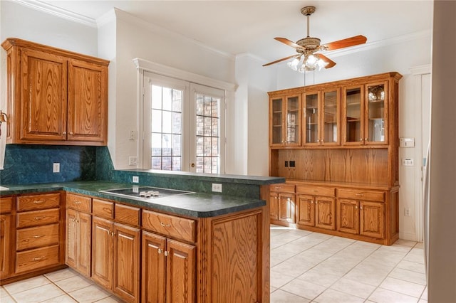 kitchen with brown cabinets, crown molding, tasteful backsplash, dark countertops, and glass insert cabinets