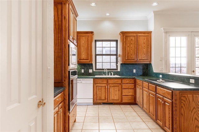 kitchen with dark countertops, white dishwasher, brown cabinets, and a sink