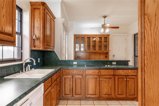 kitchen with brown cabinetry, dark countertops, a sink, and black electric cooktop