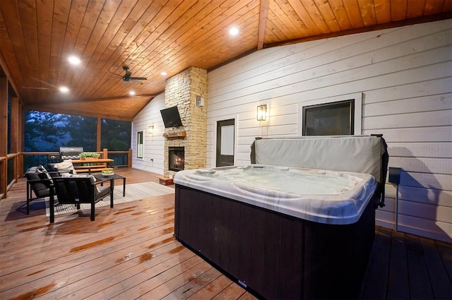 deck featuring an outdoor stone fireplace and a hot tub