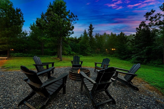 patio terrace at dusk featuring a lawn and an outdoor fire pit