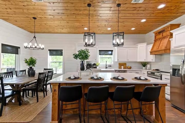 kitchen with white cabinetry, hanging light fixtures, a kitchen island, and appliances with stainless steel finishes