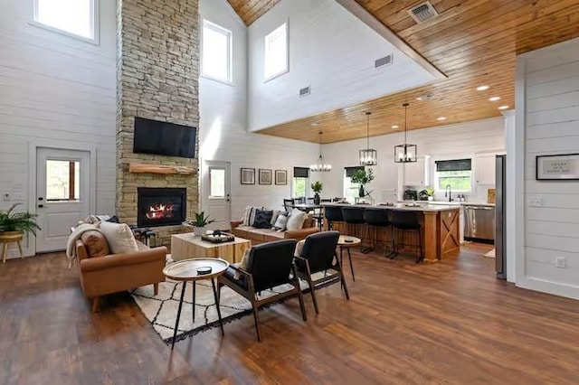 living room with a fireplace, wood ceiling, dark wood-type flooring, and plenty of natural light