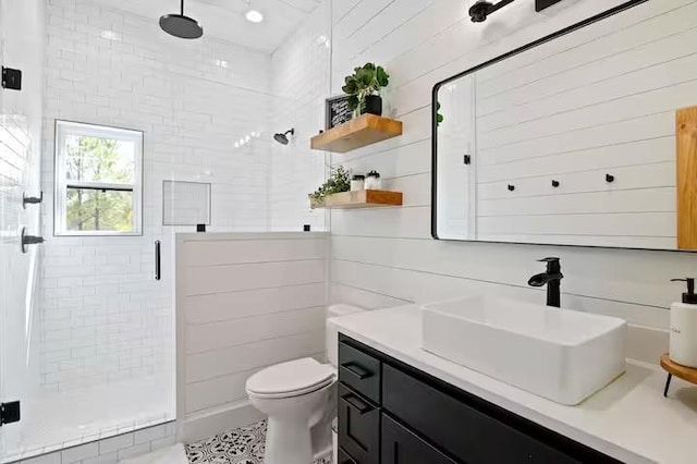 bathroom with vanity, toilet, tile walls, and a shower with shower door