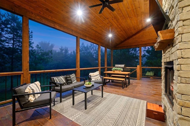 sunroom featuring vaulted ceiling, an outdoor stone fireplace, ceiling fan, and wood ceiling