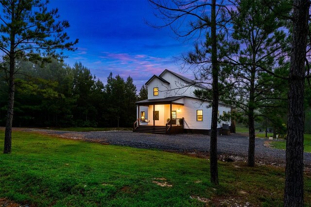 back house at dusk with a yard and a porch