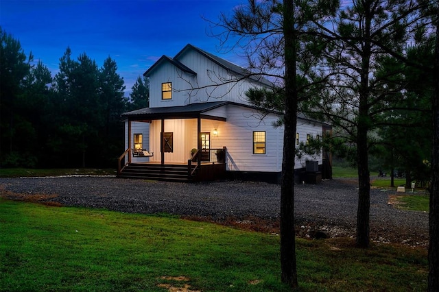 back house at dusk featuring a lawn