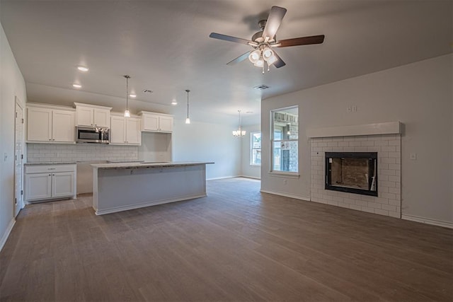 kitchen featuring white cabinets, pendant lighting, a center island with sink, and hardwood / wood-style flooring