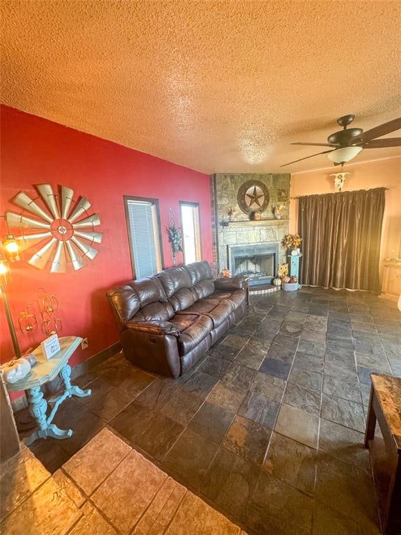 unfurnished living room featuring a stone fireplace, ceiling fan, and a textured ceiling